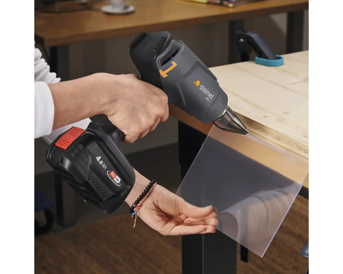 Eine Person verwendet eine Steinel MH 1 Akku Heißluftpistole zum Erhitzen eines Kunststoffstücks