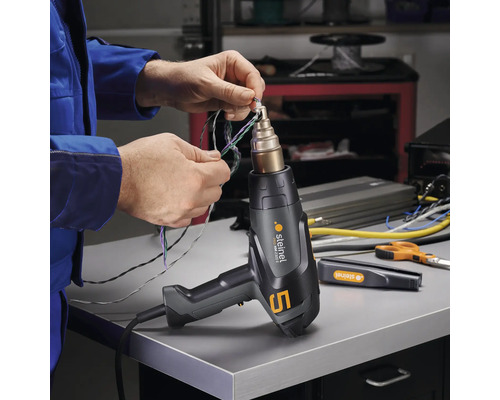 Mann verwendet Heißluftpistole von Steinel zum Verbinden von Kabeln.