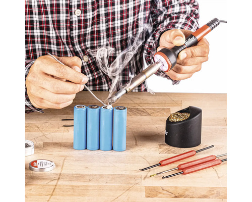 Löten von Batterien mit Lötkolben, Lötzinn und Werkzeugen auf einer Werkbank.
