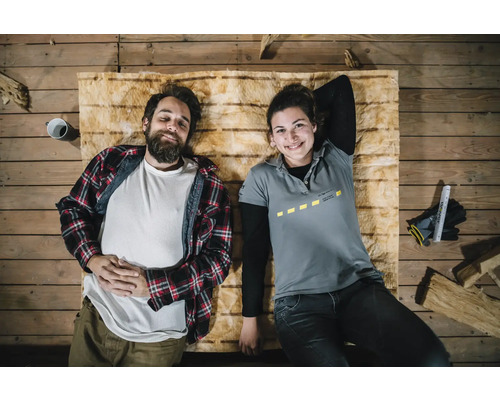 Zwei Personen liegen entspannt auf Dämmwolle auf einem Holzboden