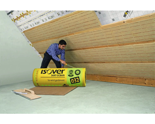 Ein Mann schneidet eine Rolle Isover Dämmwolle zur Dachisolierung.