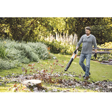 Mann benutzt einen Laubbläser im Garten, um Herbstlaub zu entfernen