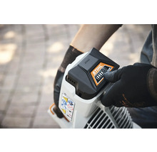 Person setzt einen Stihl Akku in ein Gartengerät ein.
