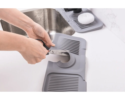 Zuschneidbare Spülbeckenmatte aus Kunststoff wird mit einer Schere angepasst.