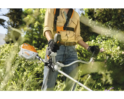 Eine Person bedient einen Rasentrimmer im Garten.