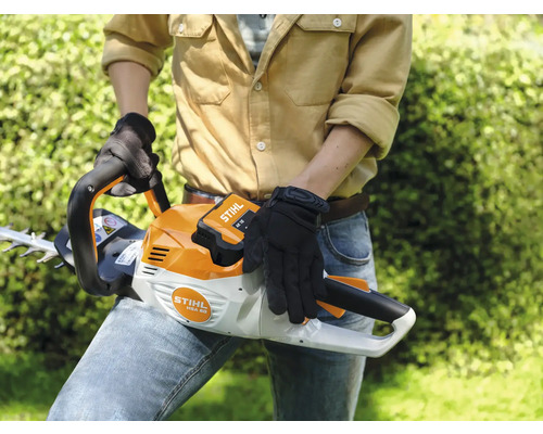 Eine Person hält eine Akku-Heckenschere der Marke Stihl.