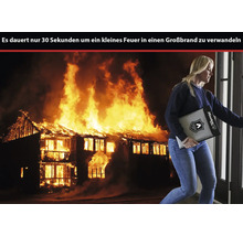 Eine Frau trägt eine feuerfeste Dokumententasche von Master Lock vor der Kulisse eines brennenden Hauses.