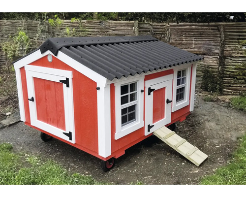 Mobiles rotes Hühnerhaus mit schwarzem Dach, weißen Akzenten, Fenstern und einer Rampe auf Rädern.