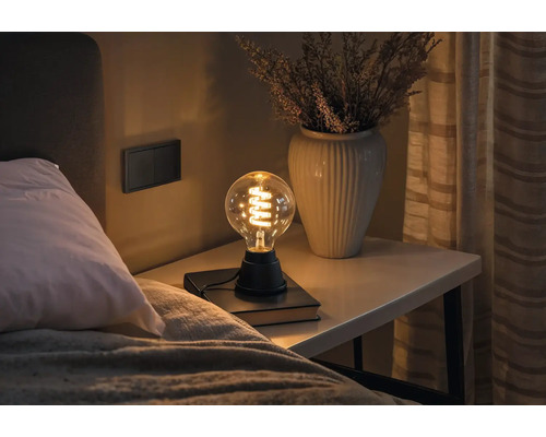 Nachttisch mit Lampe und Vase in Schlafzimmerumgebung