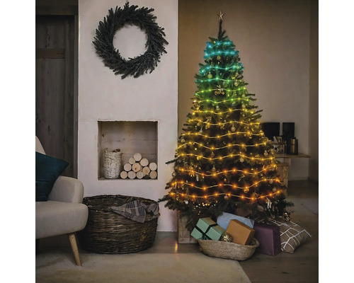 Dekorierter Weihnachtsbaum mit Lichterkette neben Kamin und Kranz