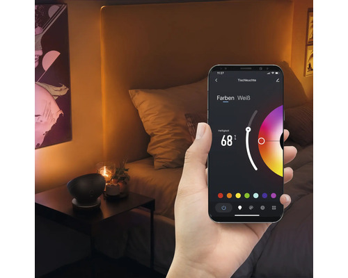 Ein Smartphone in der Hand zeigt eine App zur Steuerung einer Tischleuchte in einem Schlafzimmer.