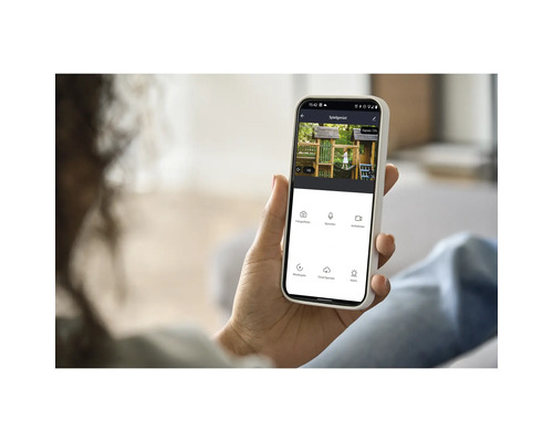 Eine Person hält ein Smartphone in der Hand, auf dem eine Kinderspielanlage zu sehen ist.