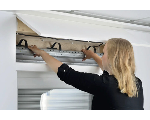 Frau montiert einen Rollladenkasten im Innenbereich