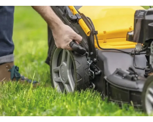 Eine Person bedient einen Rasenmäher auf einer Rasenfläche.