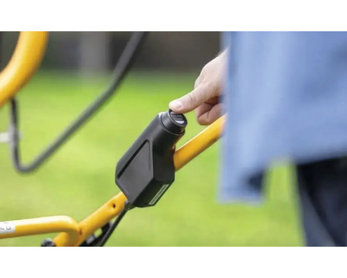 Nahaufnahme einer Hand, die einen Startknopf an einem Rasenmäher betätigt.