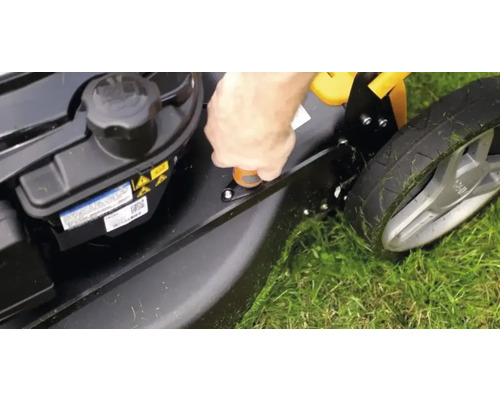 Detailaufnahme eines Rasenmähers, der auf Gras steht und bei dem die Schnitthöhe eingestellt wird