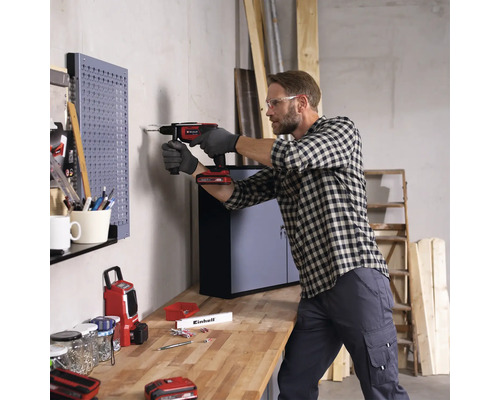 Mann bohrt mit einem Akku-Bohrschrauber in eine Wand in einer Werkstatt