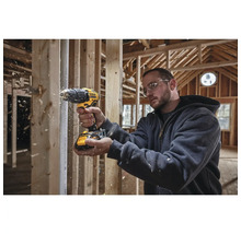 Handwerker bohrt mit einem Akku-Bohrschrauber von Dewalt in einem Rohbau Holz.