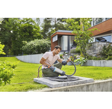 Mann benutzt eine Gardena Regenfasspumpe im Garten zur Gartenbewässerung.