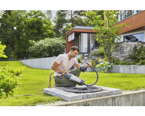 Mann benutzt eine Gardena Regenfasspumpe im Garten zur Gartenbewässerung.