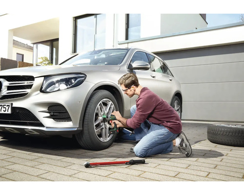 Mann wechselt mit einem Schlagschrauber einen Reifen an einem Auto.
