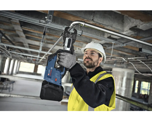 Ein Handwerker verwendet eine Akku-Presszange von Bosch zum Verpressen eines Metallrohrs.