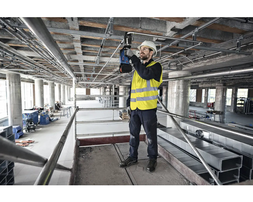 Handwerker auf einem Gerüst bei der Installation von Rohren und Leitungen an einer Decke.