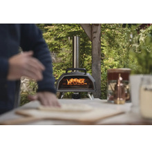 Holzbefeuerter Pizzaofen mit Bediener beim Zubereiten einer Pizza