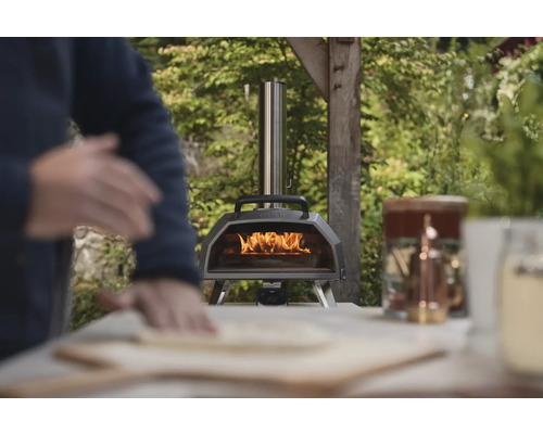 Holzbefeuerter Pizzaofen mit Bediener beim Zubereiten einer Pizza