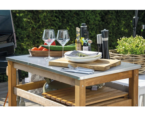 Grilltisch mit Geschirr, Gläsern, Gewürzen, Ölen, Schneidebrett und Gemüse