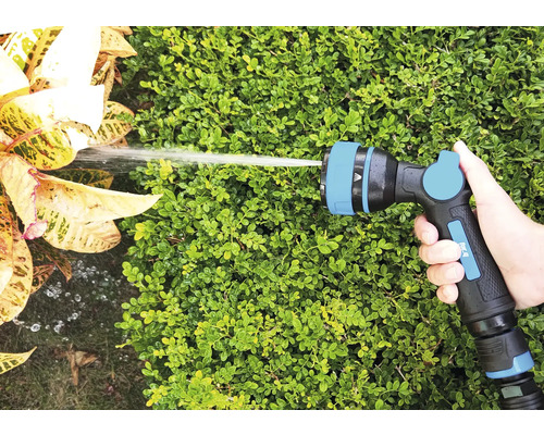 Hand hält Gartenschlauch-Spritzpistole beim Bewässern von Pflanzen