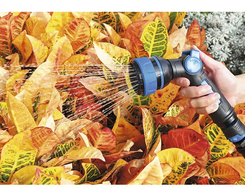 Eine Person bewässert Pflanzen mit einer Gartenspritze.