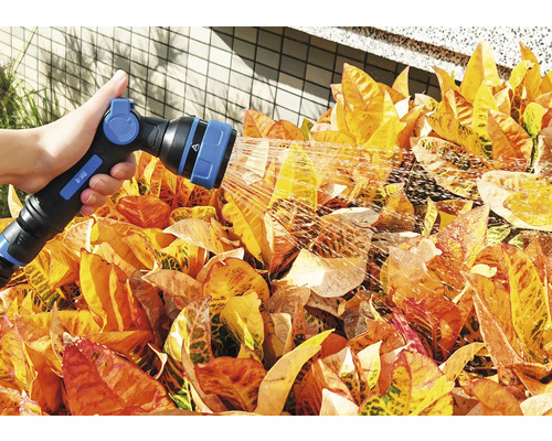 Eine Person bewässert mit einer Gartenspritze Pflanzen.