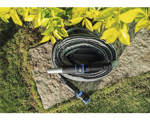 Flexibler Gartenschlauch auf einem Stein im Garten