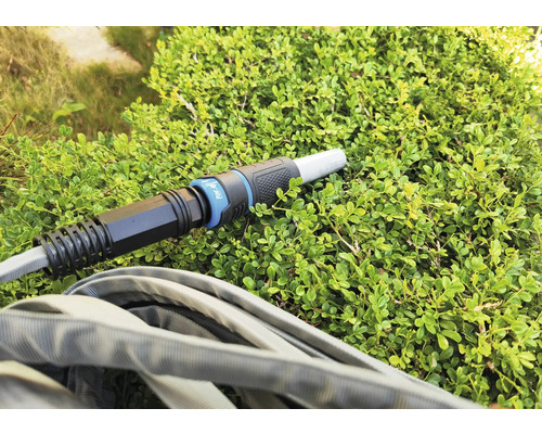 Gartenschlauch mit Anschlussstück auf einer Grünpflanze