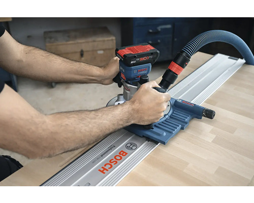 Eine Person verwendet eine Akku-Oberfräse mit Führungsschiene von Bosch auf einem Werkstück.
