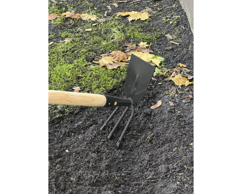 Gartengerät mit Holzstiel und Dreizackzinken im Beet