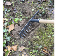 Gartenrechen im Einsatz zum Einebnen von Erde im Garten.