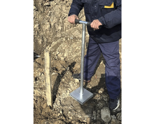 Mann verdichtet Boden mit einem Handstampfer