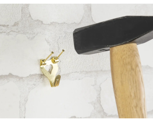 Hammer und Bilderhaken an einer Wand befestigt