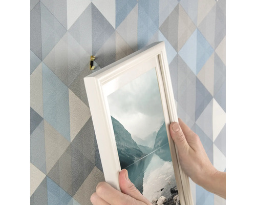 Person hängt Bild mit Bilderhaken an Wand