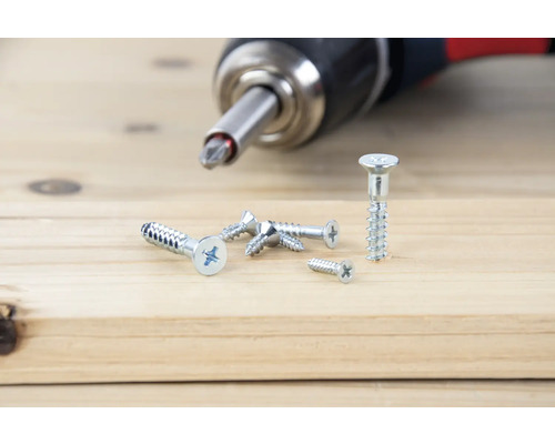 Akkuschrauber mit Schrauben auf Holzbrett