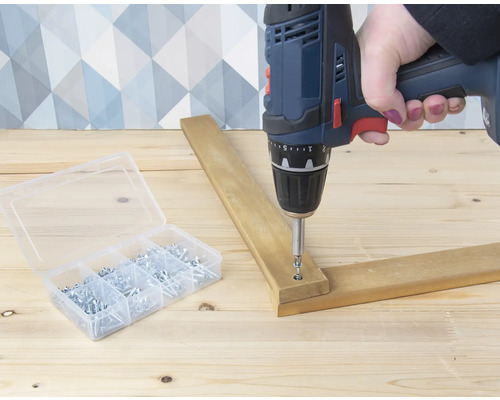 Akkuschrauber beim Verschrauben von Holz und einer Schraubenbox