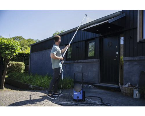 Mann reinigt Hausdach mit Hochdruckreiniger