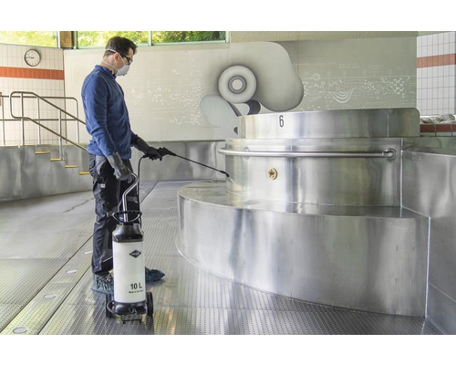 Ein Mann reinigt einen Edelstahlpool mit einem 10 Liter Drucksprüher.