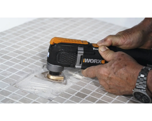 Detailansicht einer Person, die mit einem Multifunktionswerkzeug Fliesen bearbeitet, Marke Worx