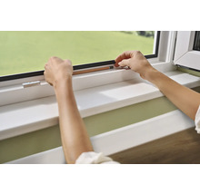 Hände befestigen Dichtungsband an einem Fensterrahmen