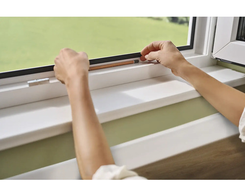 Hände befestigen Dichtungsband an einem Fensterrahmen