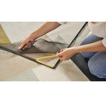 Person befestigt ein Fliegengitter mit einem Werkzeug am Fensterrahmen