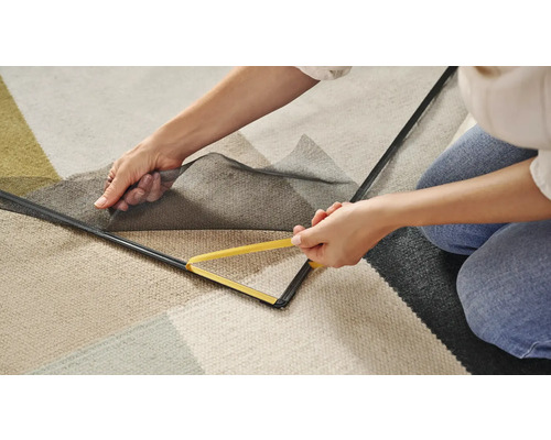 Person befestigt ein Fliegengitter mit einem Werkzeug am Fensterrahmen